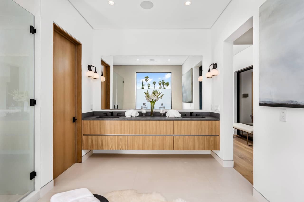 Bathroom with a floating wood vanity, black fixtures and a wide mirror