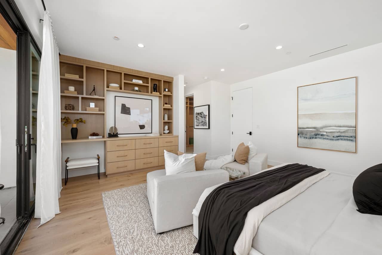 Bedroom with built-in wood shelving and a reading chair