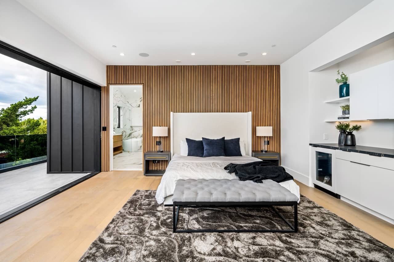 Bedroom with a wood accent wall and sliding glass doors to a balcony