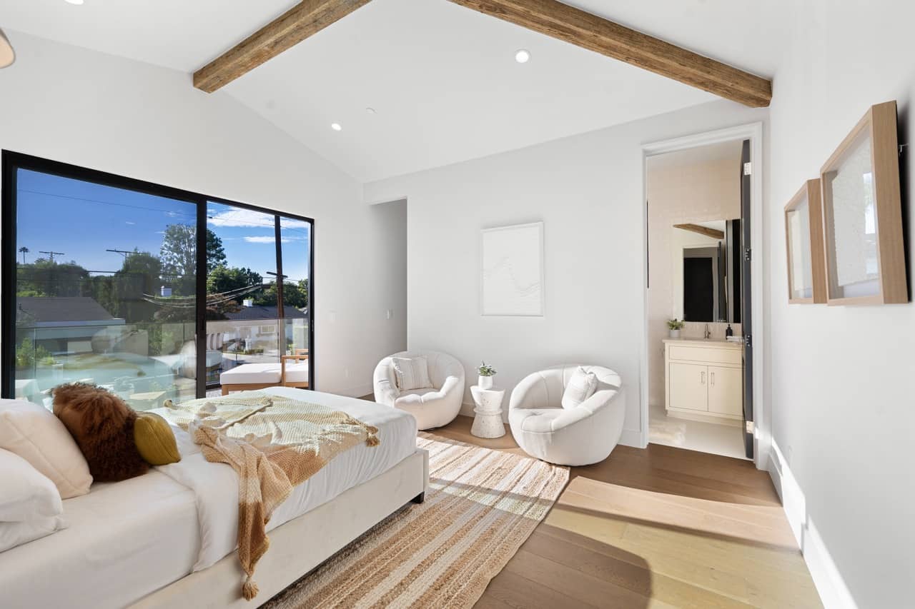 Bedroom with wood ceiling beams and sliding doors to the yard