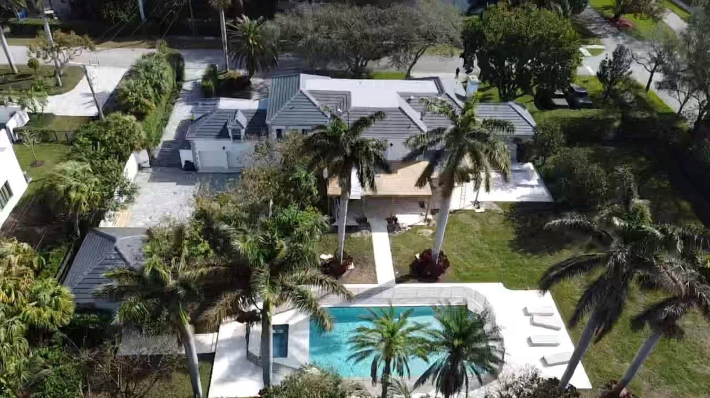 Aerial view of a South Florida estate with a gray tile roof, palm trees and a pool