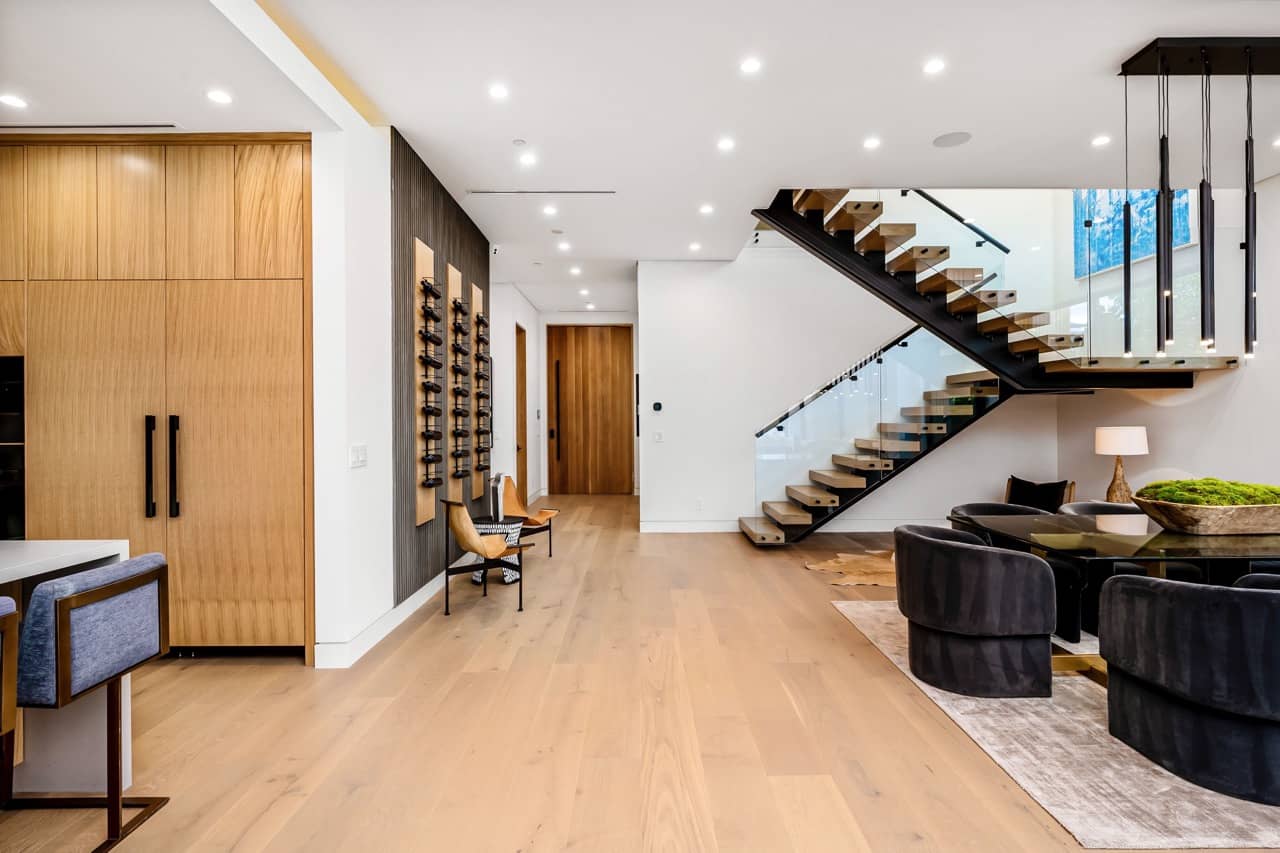 Entry with a floating staircase, a glass railing and tall wood doors