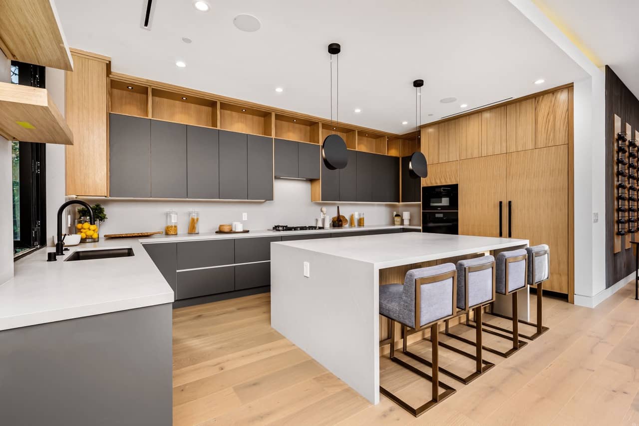 Modern kitchen with a large island, gray and wood cabinets and black pendant lights
