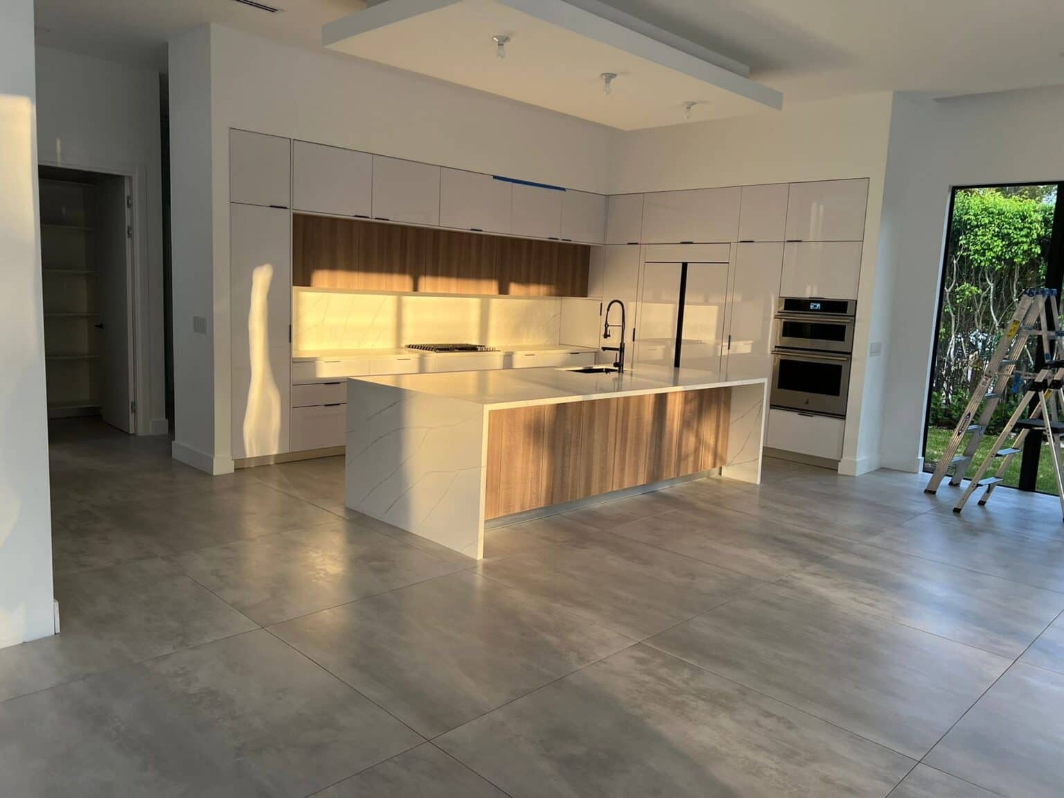 Kitchen with white and wood cabinetry, a waterfall island and under-cabinet lighting
