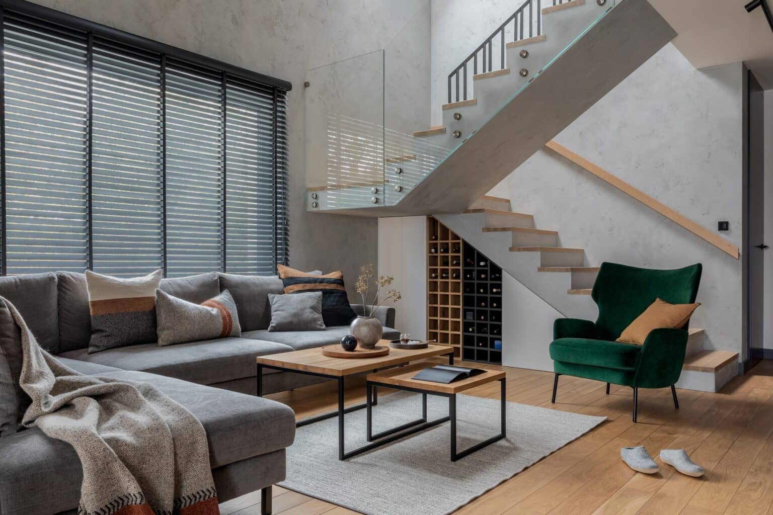 Living room with a gray sectional, a green armchair and an open staircase
