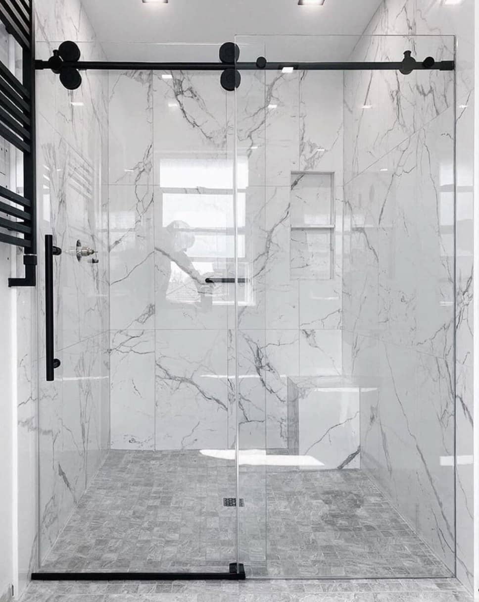 Walk-in shower with floor-to-ceiling marble-look tile and matte black sliding-door hardware