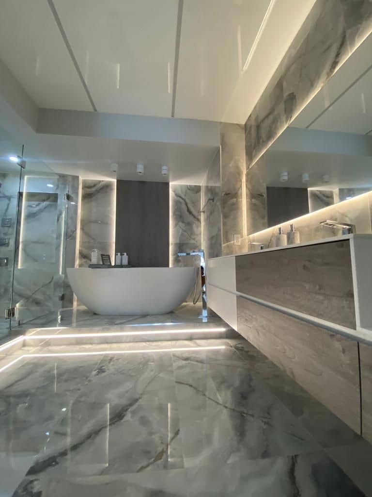 Primary bathroom with polished marble-look floors, a freestanding tub, a glass shower and a floating vanity