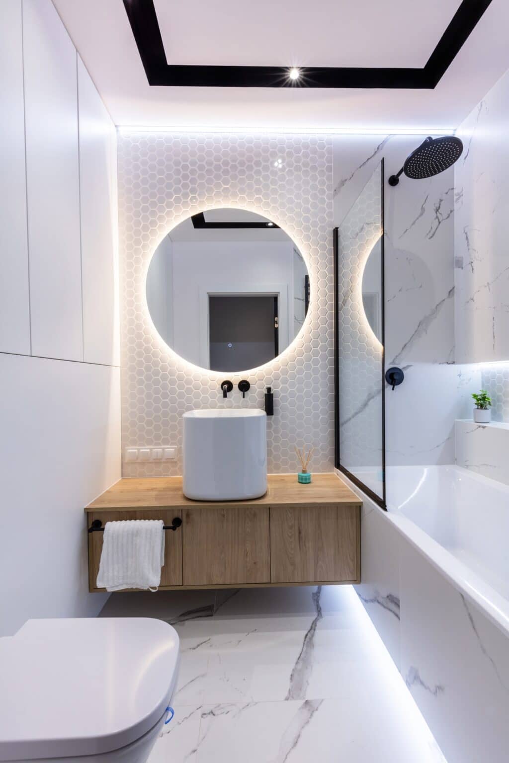 Small bathroom with a round backlit mirror, a wood shelf vanity and a glass shower