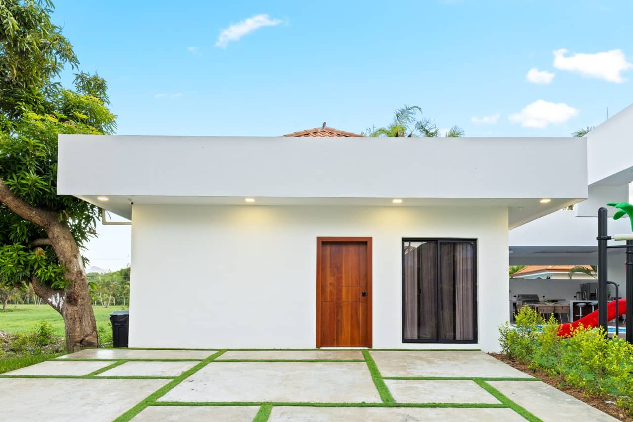 Detached single-story guest house with a wood door and a paver-and-turf courtyard