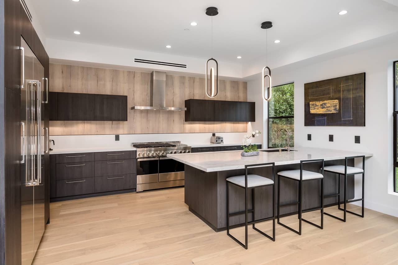 Kitchen with dark cabinetry, a long island and a row of counter stools