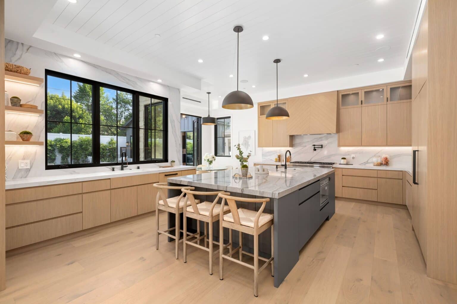 Kitchen with natural wood cabinets, a gray island and black-framed windows