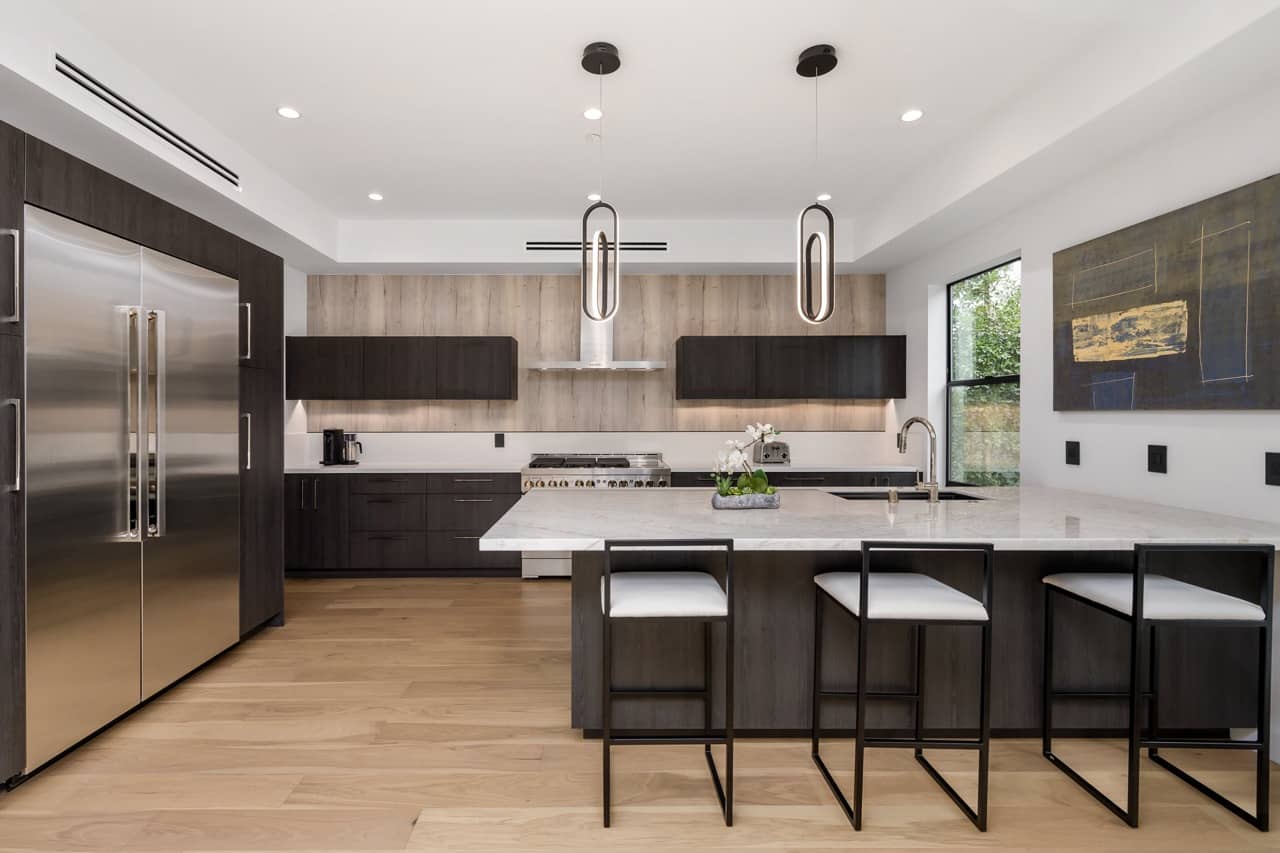 Large kitchen with wood-paneled walls, white counters and black stools