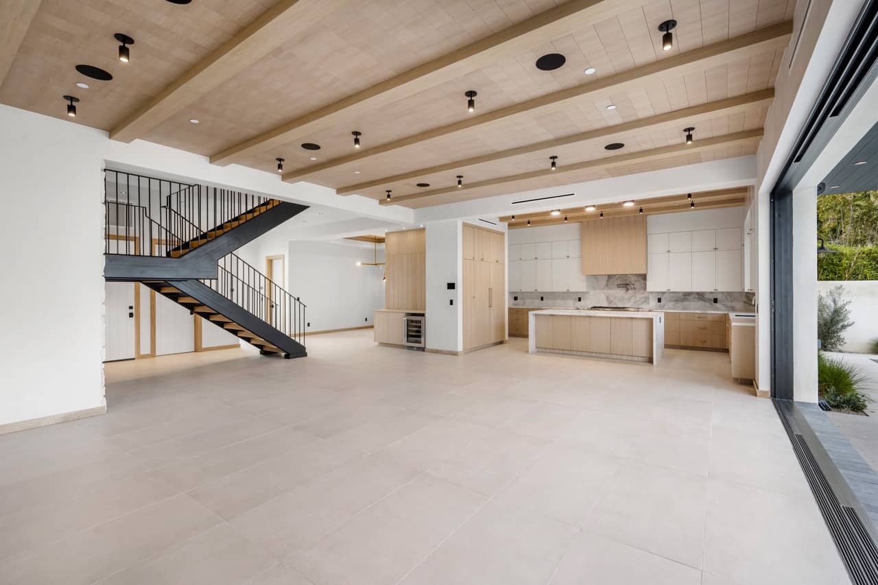 Open interior with a wood ceiling, a black steel staircase and a kitchen at the back