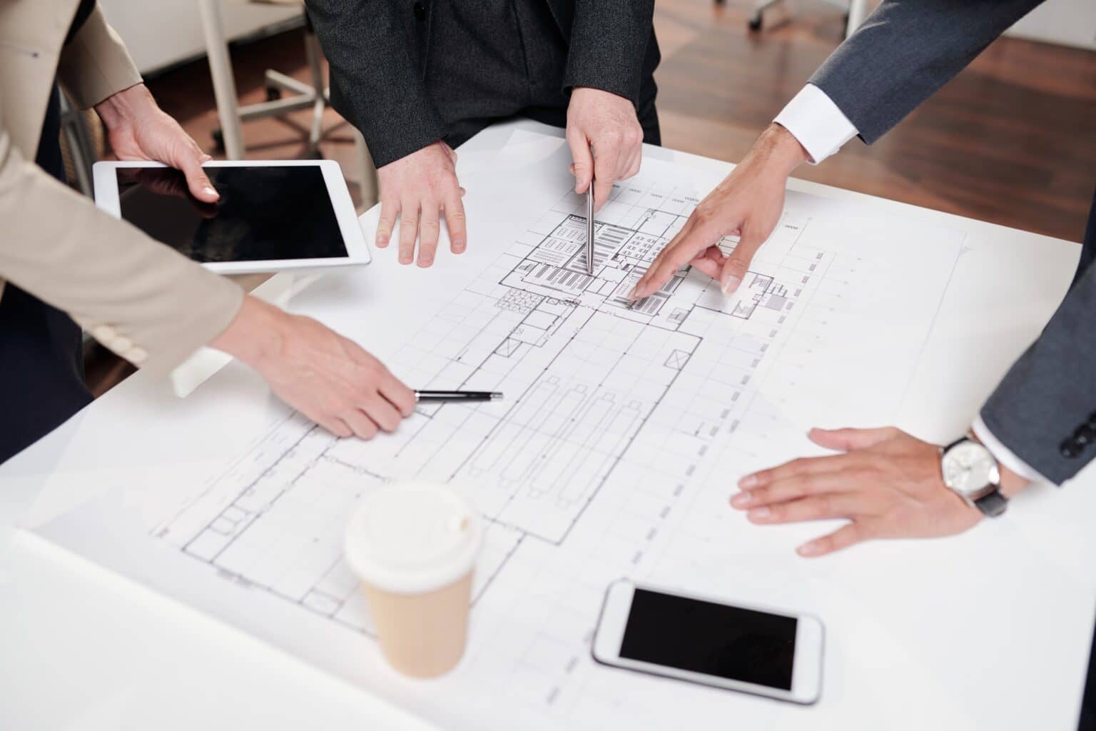 Construction plans spread on a table during a planning meeting