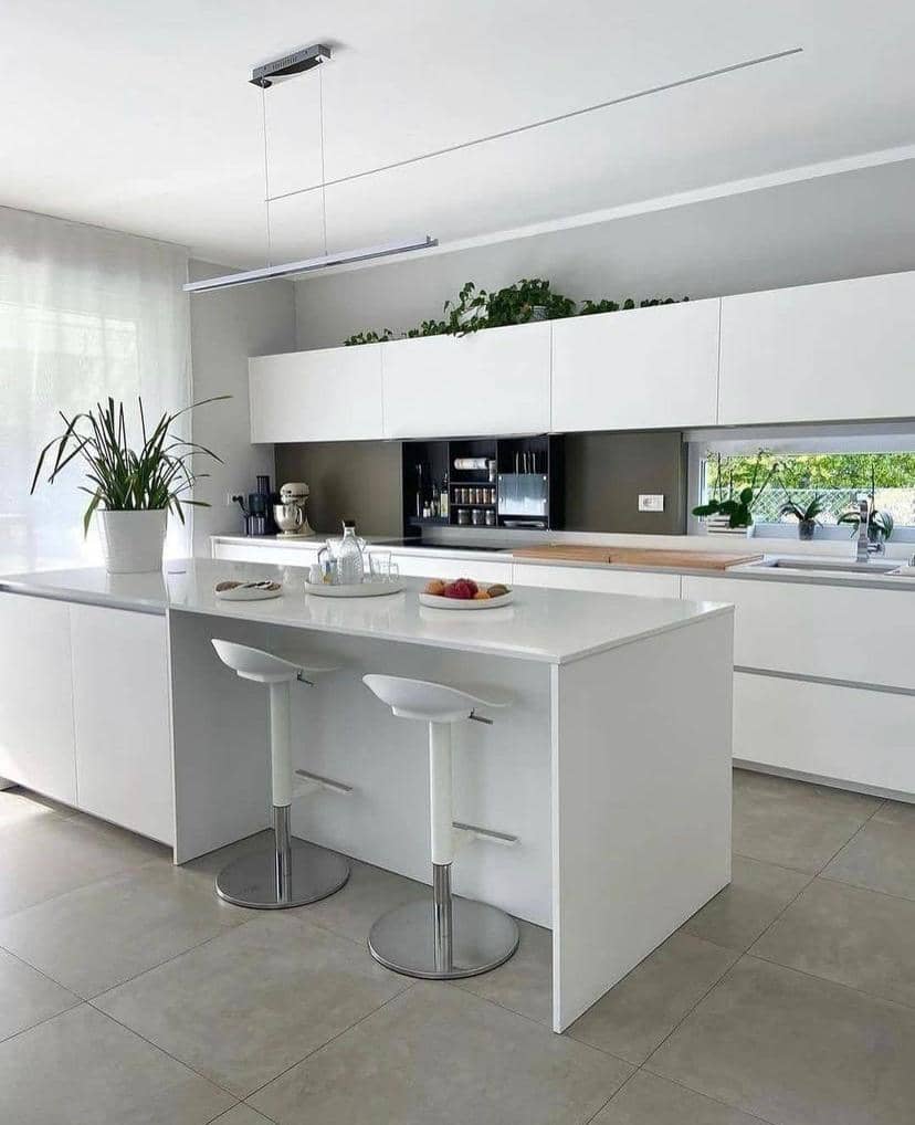 White kitchen with an island, chrome bar stools and a long open shelf